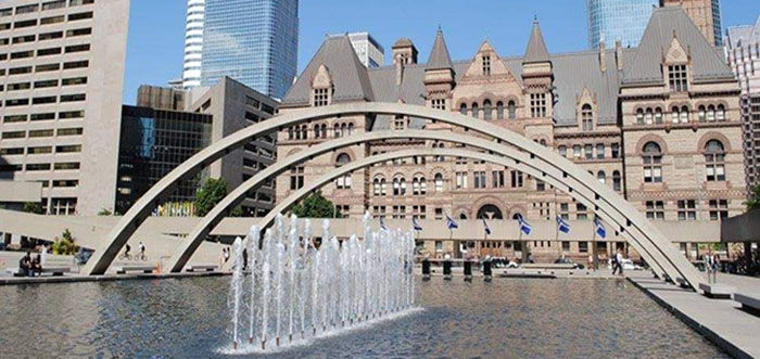 Fountain at Nathan Phillips Square, with historic buildings in the background.