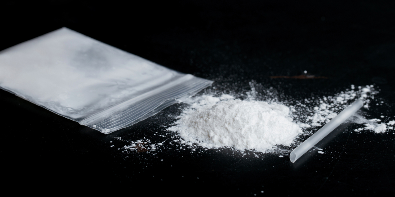 Bag of white powder (ketamine) and plastic straw to show concept of club drugs and ketamine use disorder.